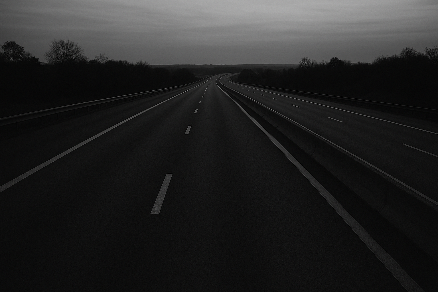 Autoroute déserte au crépuscule avec marquage au sol, photographie en noir et blanc.
